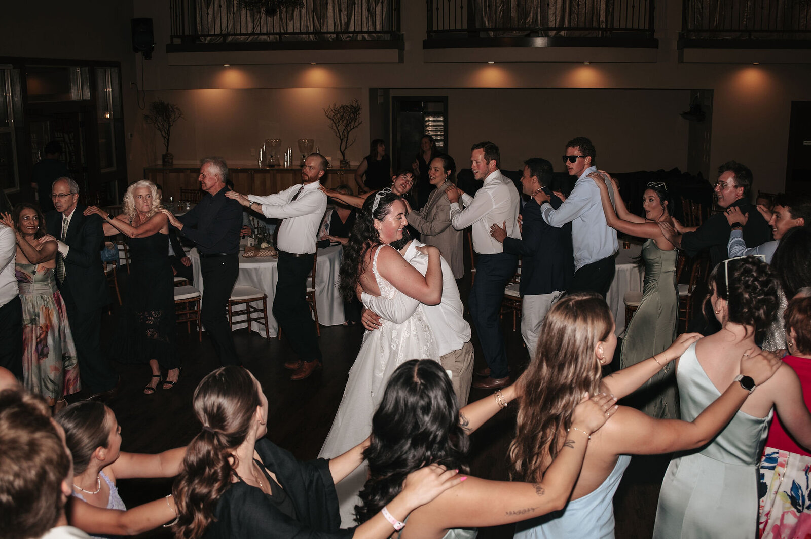 Guests dance in a joyful circle around the newlyweds during a wedding reception at Empress Estate, photographed by a Portland Oregon wedding photographer.