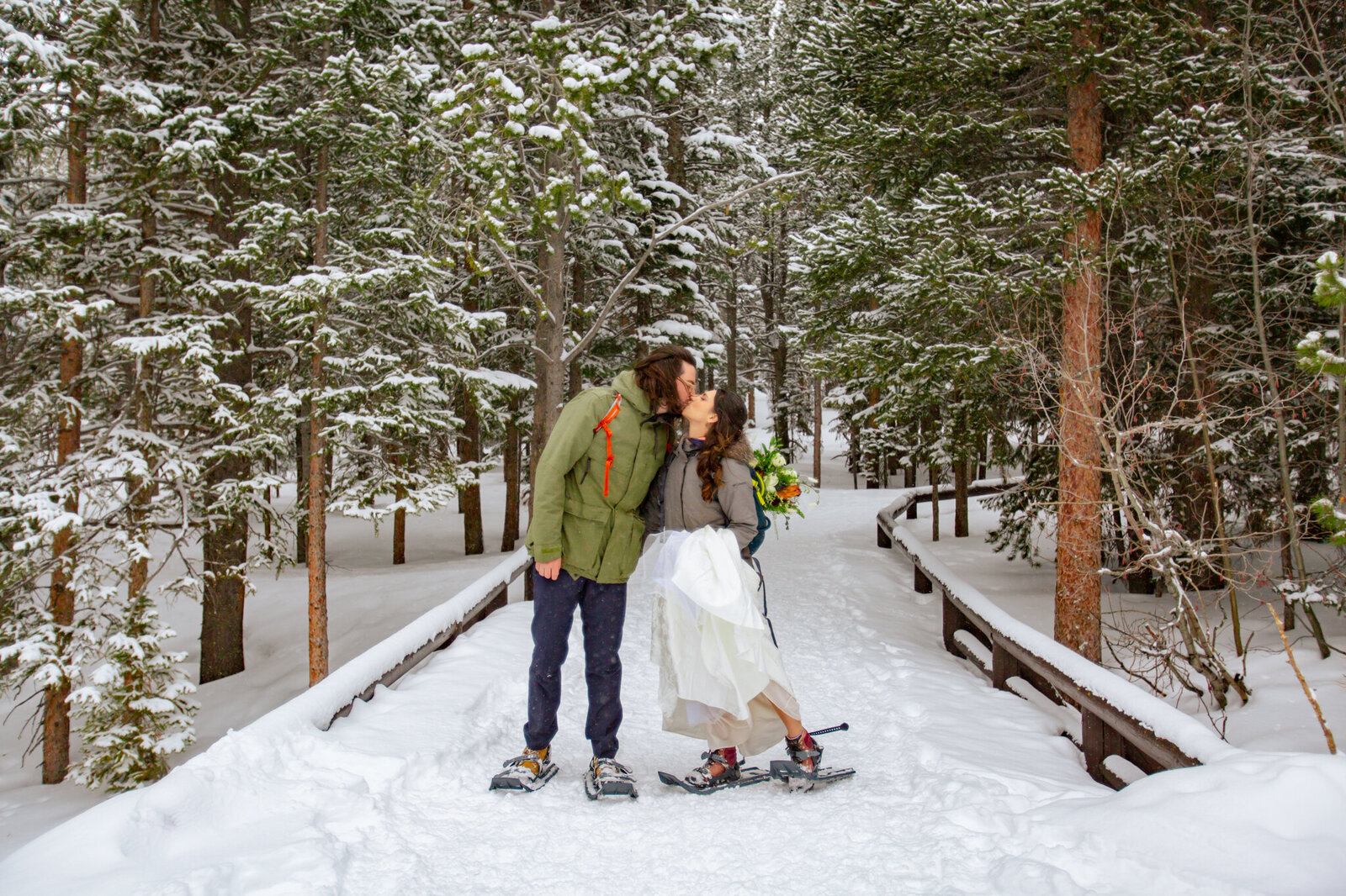 Bride and groom kiss at the beginning of the trailhead in rocky mountain national park