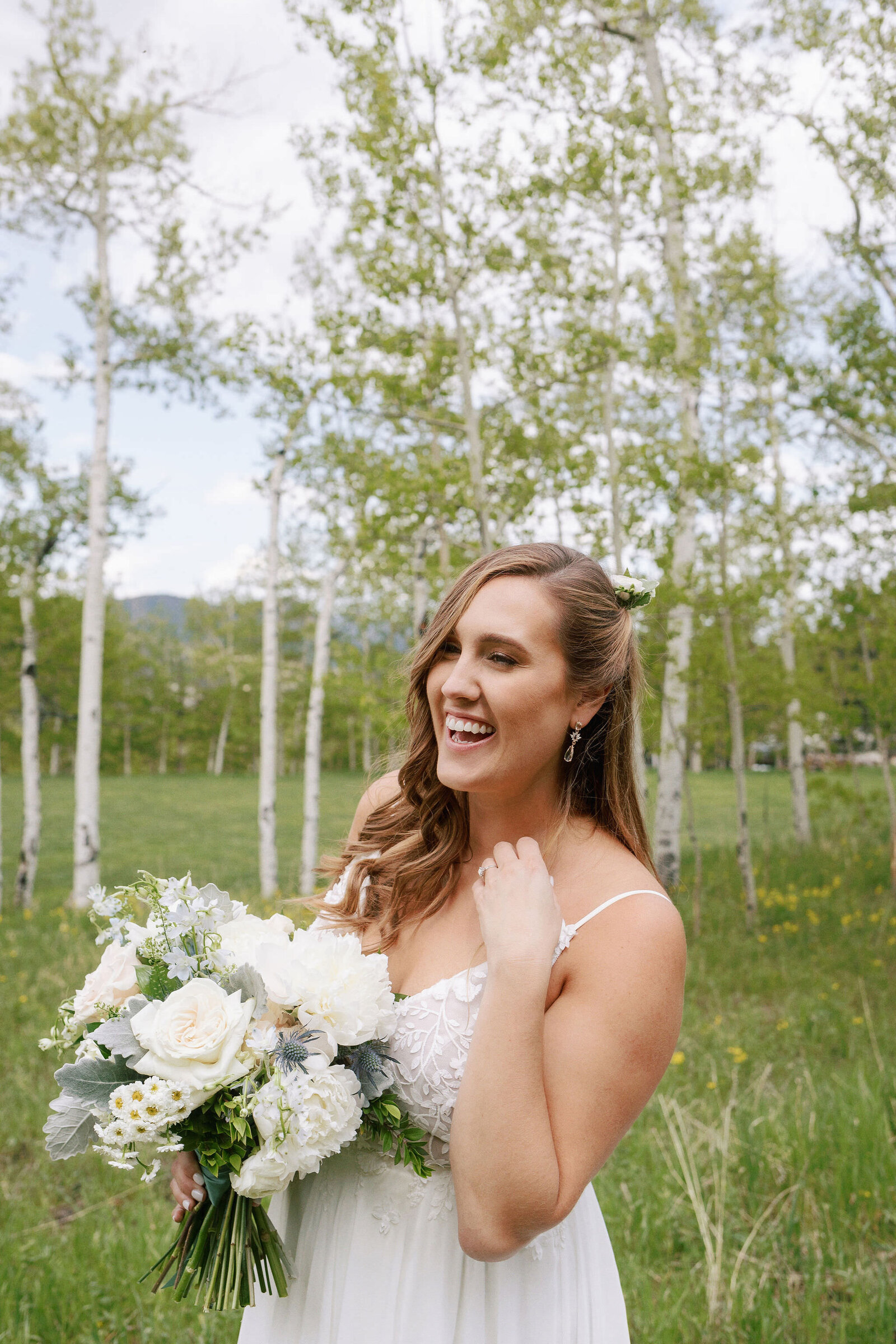 A bride laughing while holding a bouquet of flowers.
