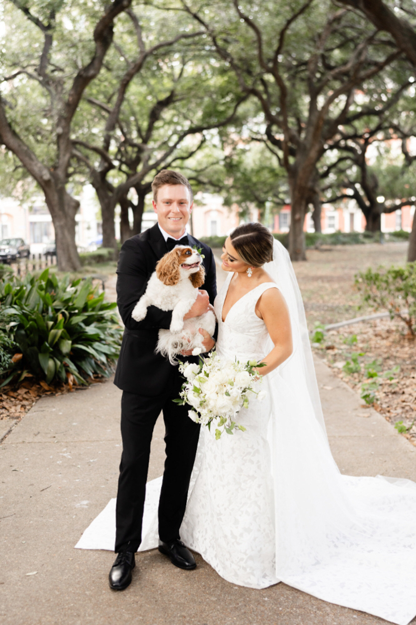 bride and groom holding dog at wedding