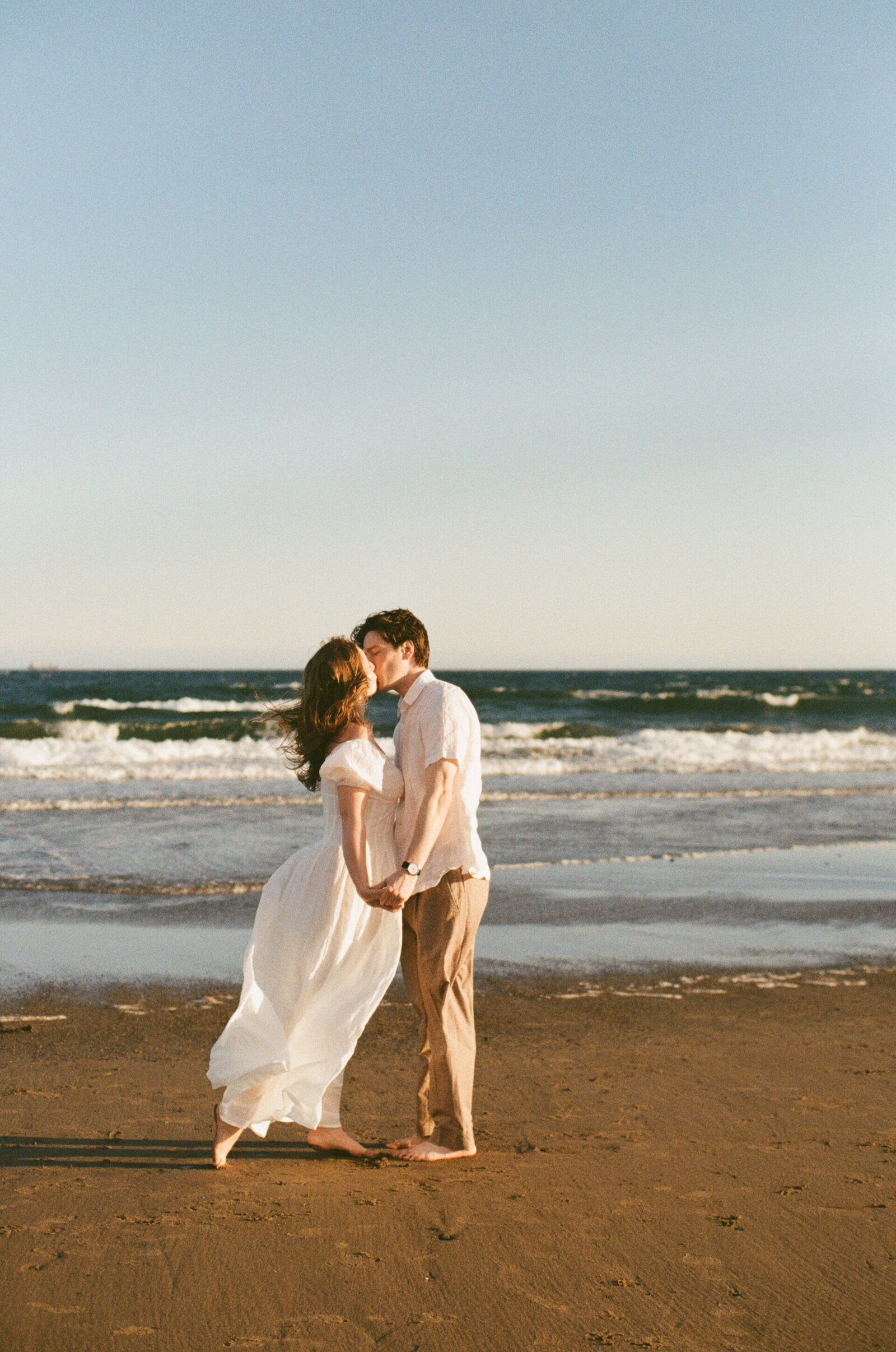 A couple kisses by the water at Conrad's Beach in Halifax.