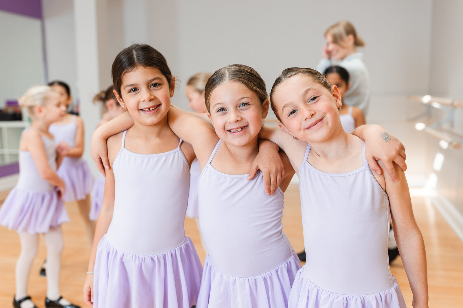 three dancers smile at the camera in a hug