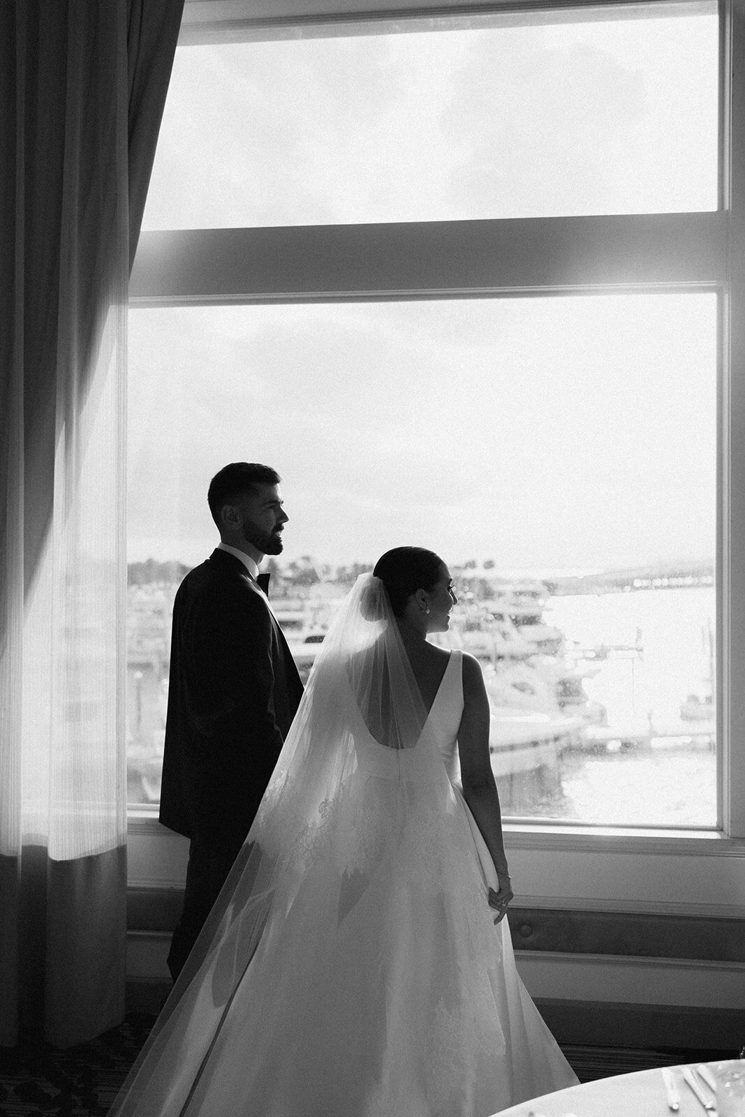 Newlywed couple looking out towards the port on the water inside of wedding venue | Sush Digital Media
