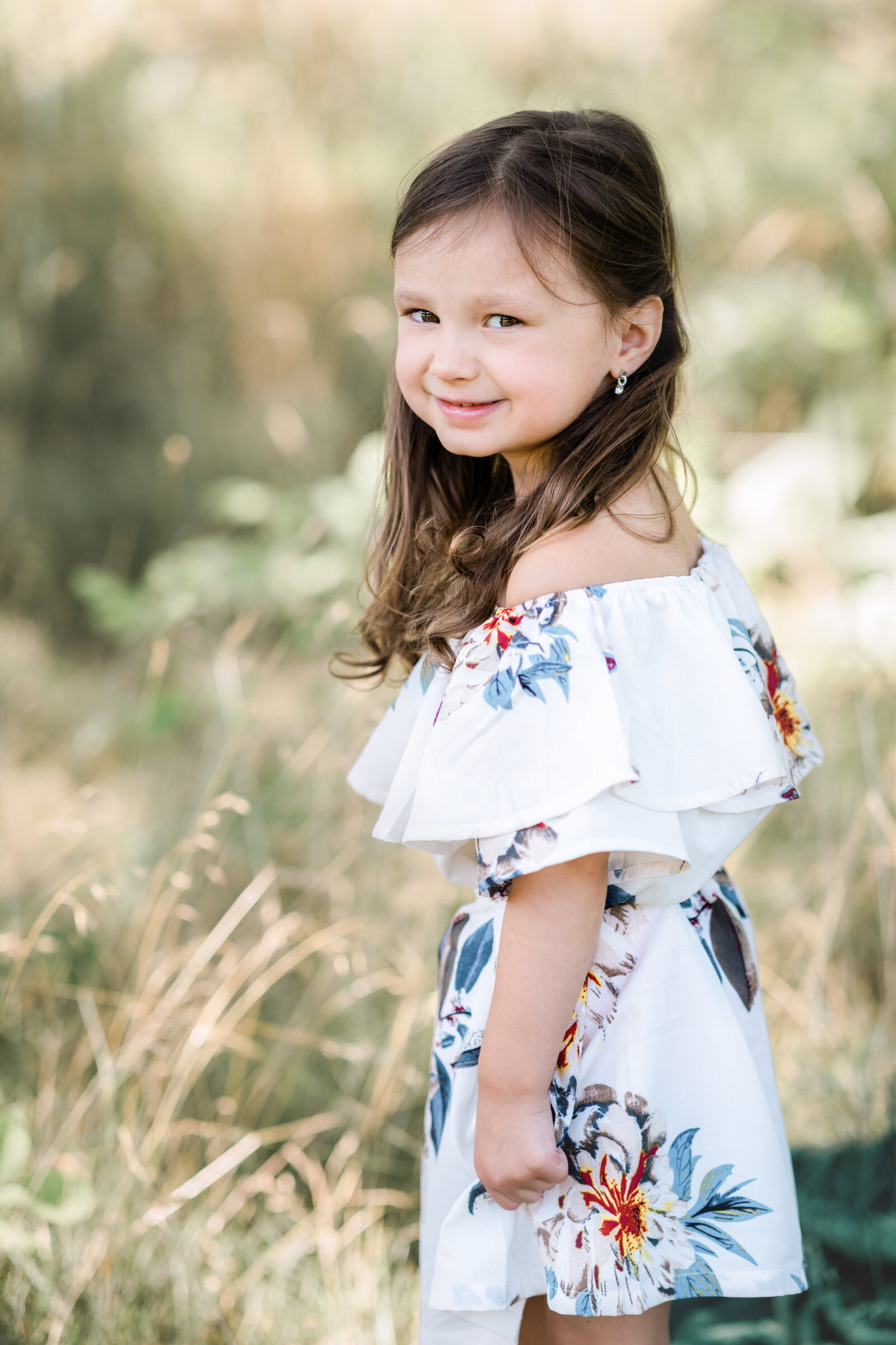 little girl in flowery dress posing for family photos