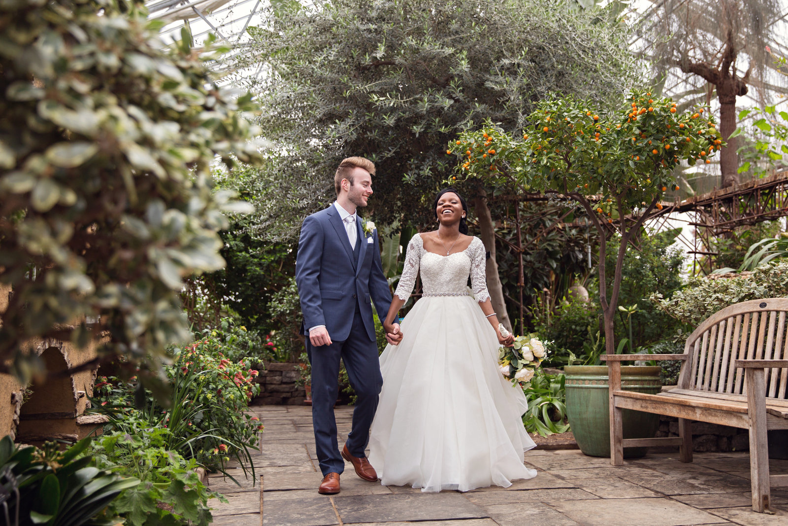 mixed race bride and groom walking in greenhouse