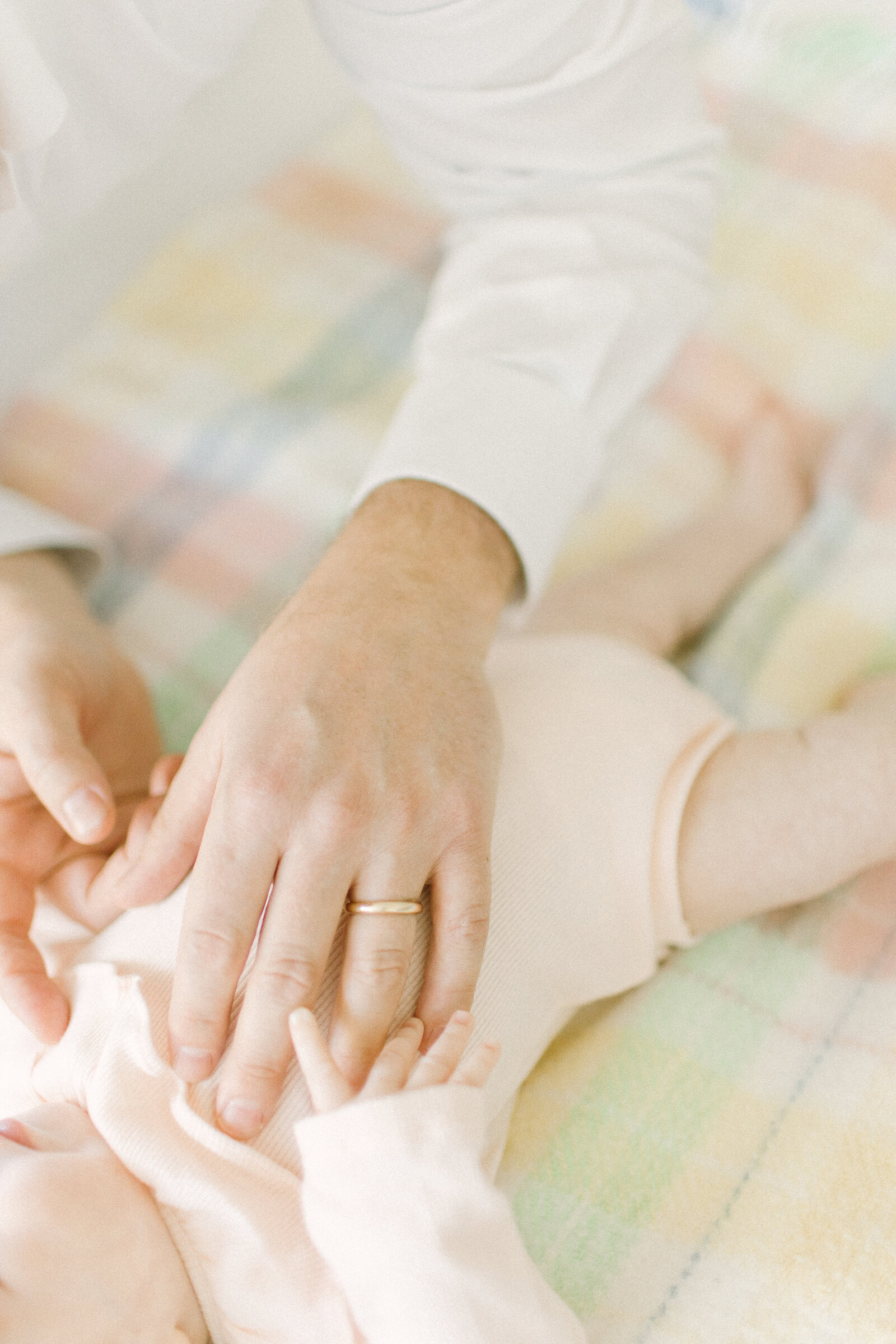 A close up image of a father resting his hand on his baby girl's stomach while she grasps his finger during photo session with Boston newborn photographer Corinne Isabelle