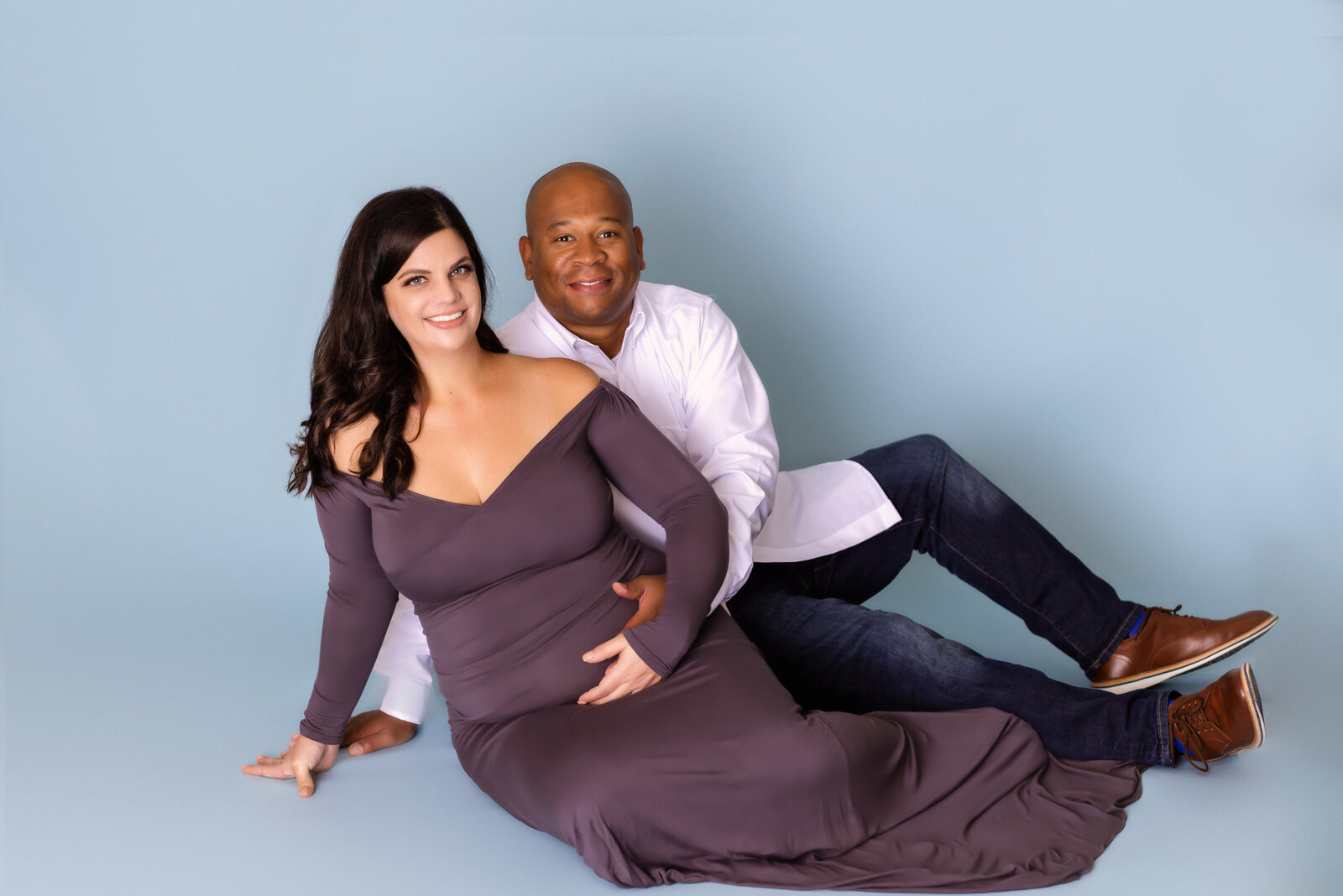 Maternity Photographer, a husband and wife recline together, she is pregnant