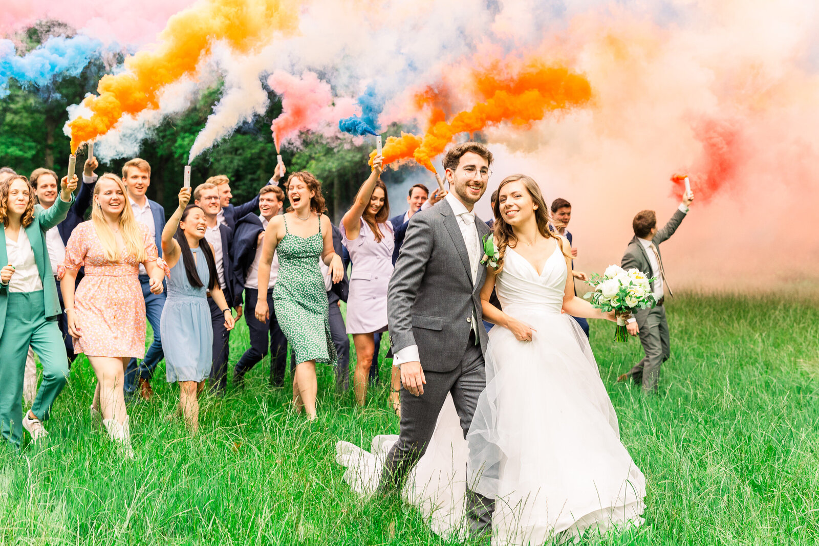 Wedding photography of young couple with friends and colorful smoke.