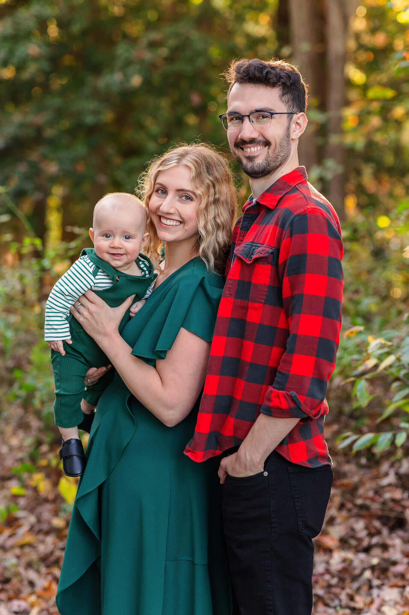 A mom and dad with their baby boy at a park at sunset.