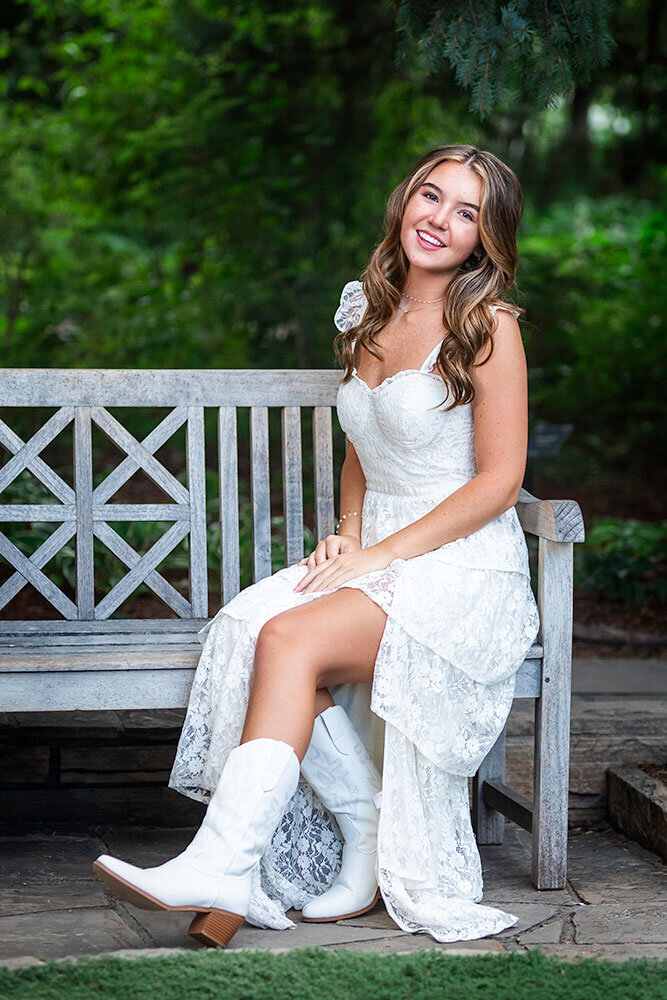 gorgeous-senior-white-dress-on-bench-classy-elegant-forest-green-background-best-colorado-senior-photographer