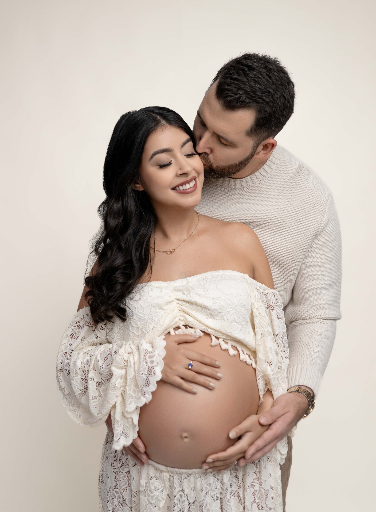 Maternity photo of Dad hugging Mom and kissing her cheek. Pregnancy photo taken by Jenni. Nikki Photography at Atlanta Photo Studio. 