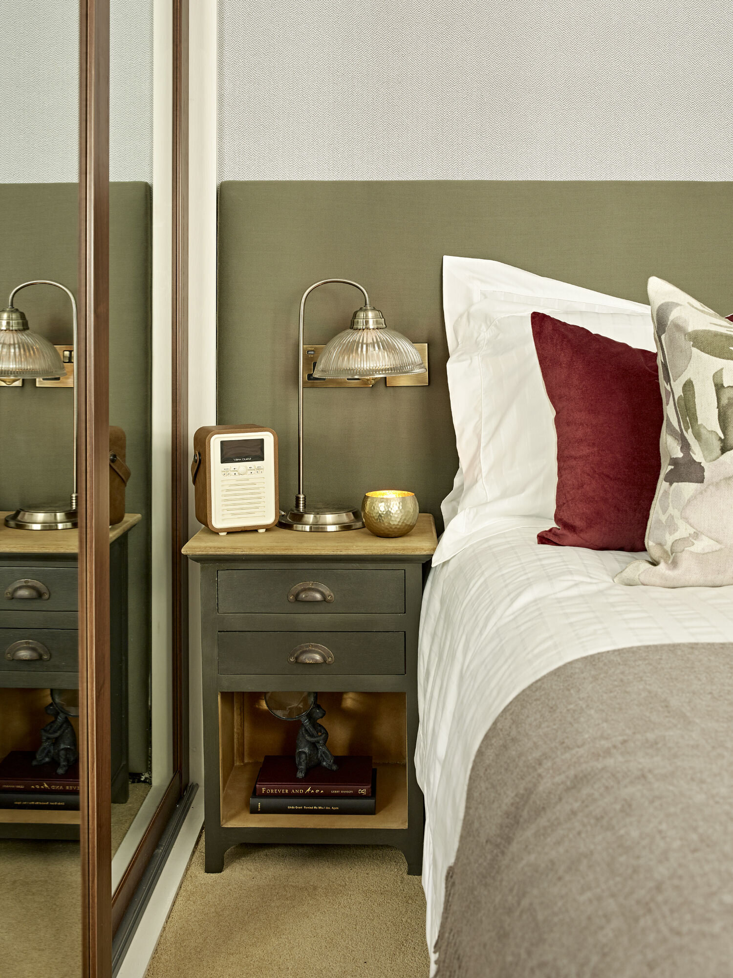 bedroom suite with mirrored wardrobe and maroon pillows on white bed.