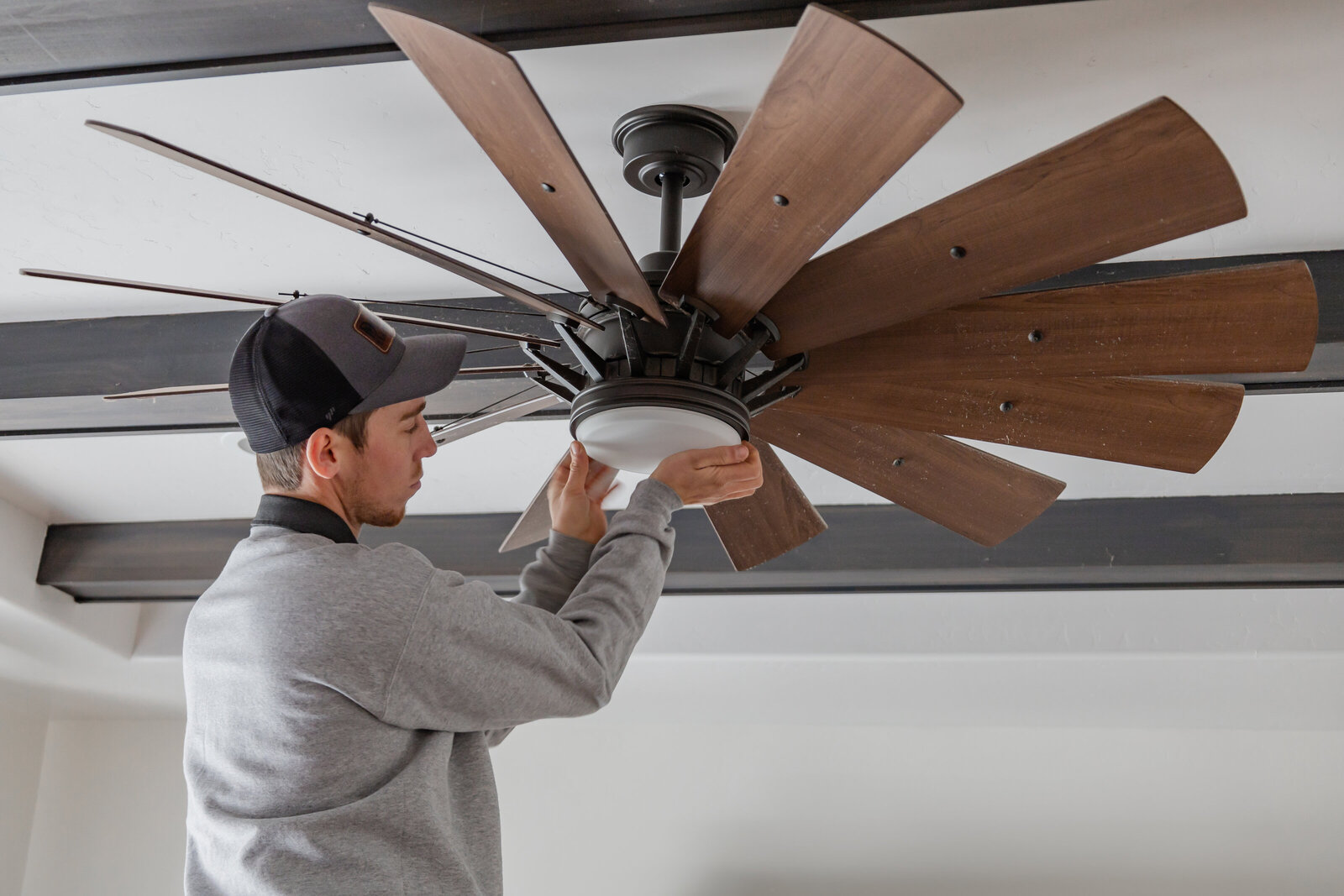 Man fixing ceiling fan in home with residential electrical services in Albuquerque