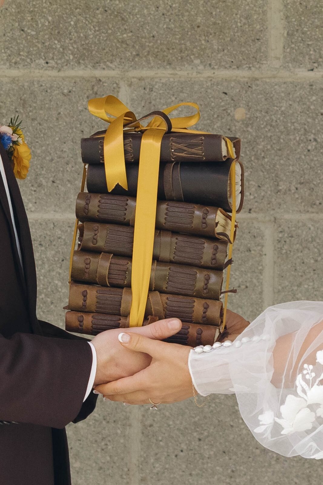 Groom handing the bride a stack of books tied with gold ribbon