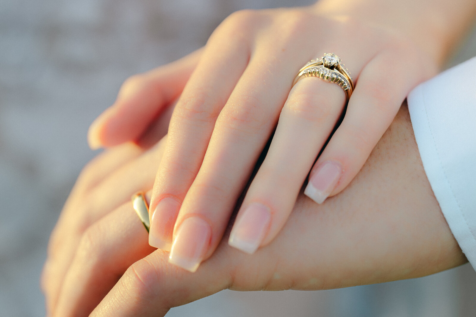 A bride and groom hold hands showing off their new wedding rings after their ceremony.