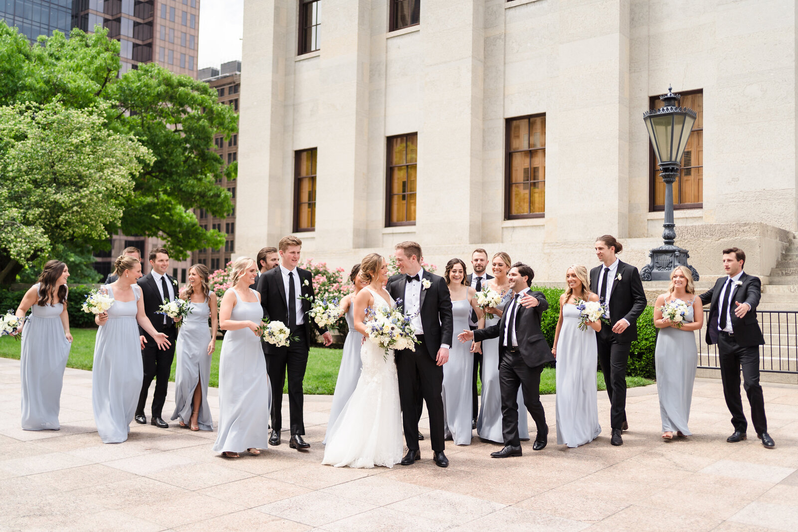 Bridal party runs towards the bride and groom on the grounds of the Ohio Statehouse