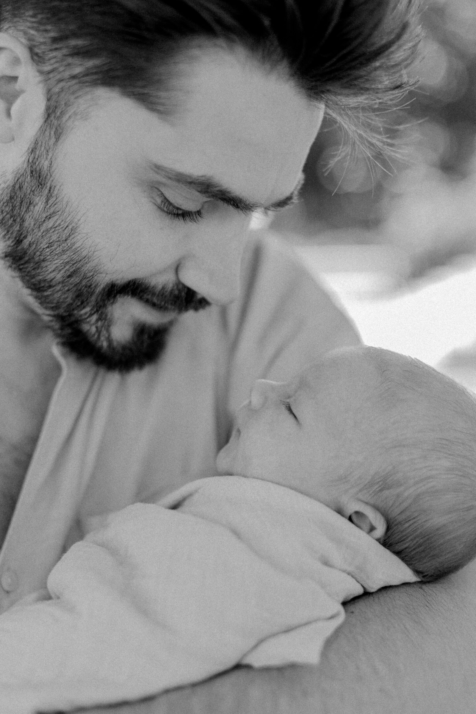 A black and white image of a father holding his newborn baby boy