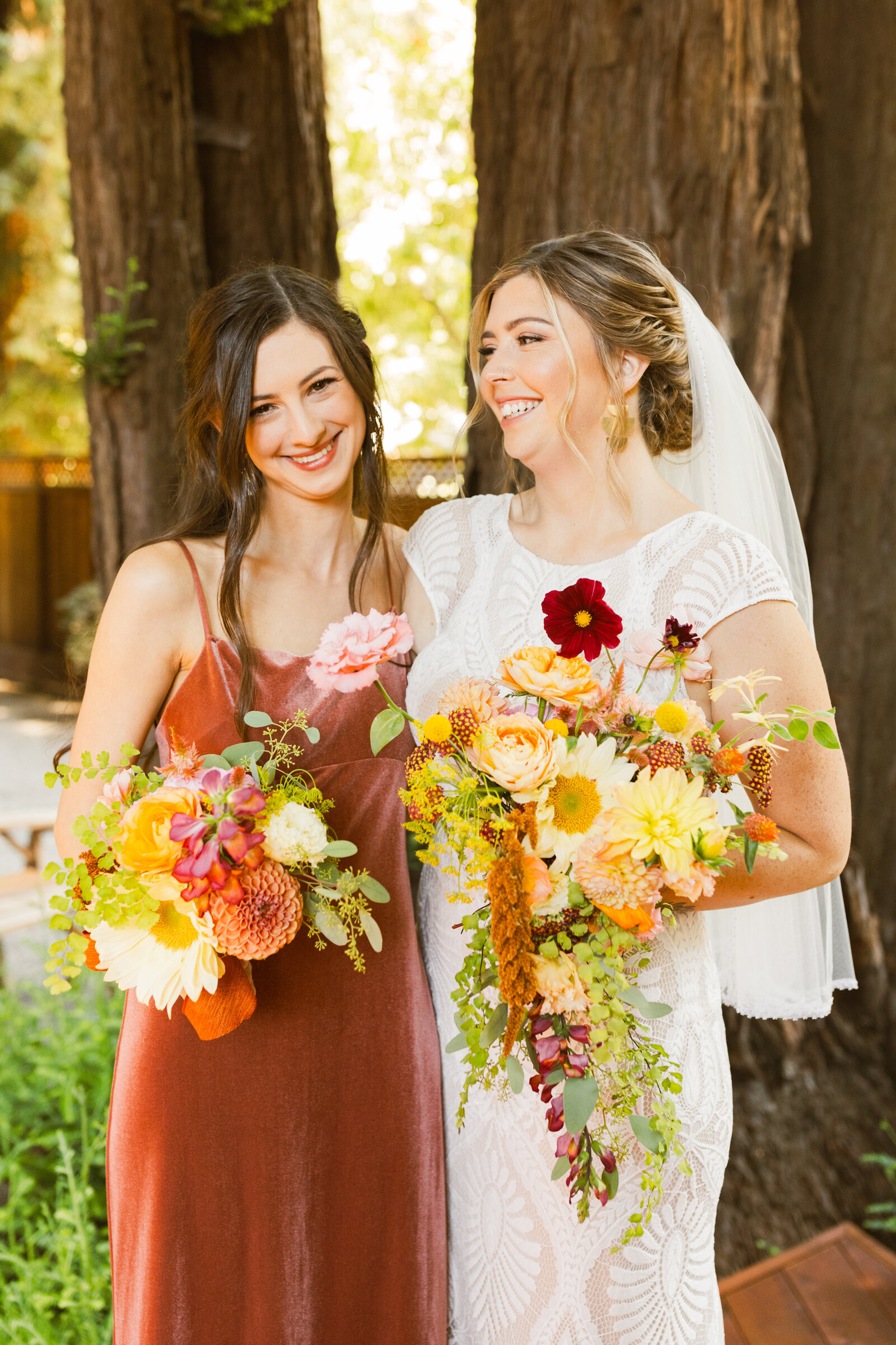 Bride and bridesmaid at her colorful wedding ceremony in Santa Cruz, California in the redwood trees.