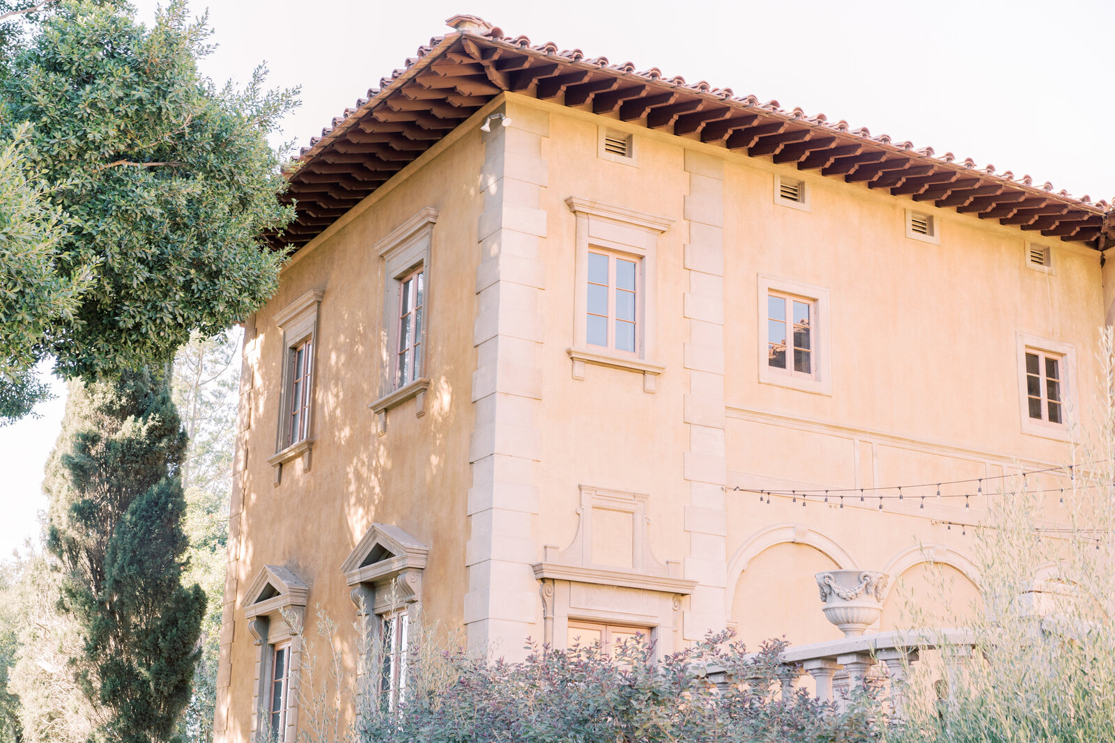 A peach-colored Spanish-style building with trees.