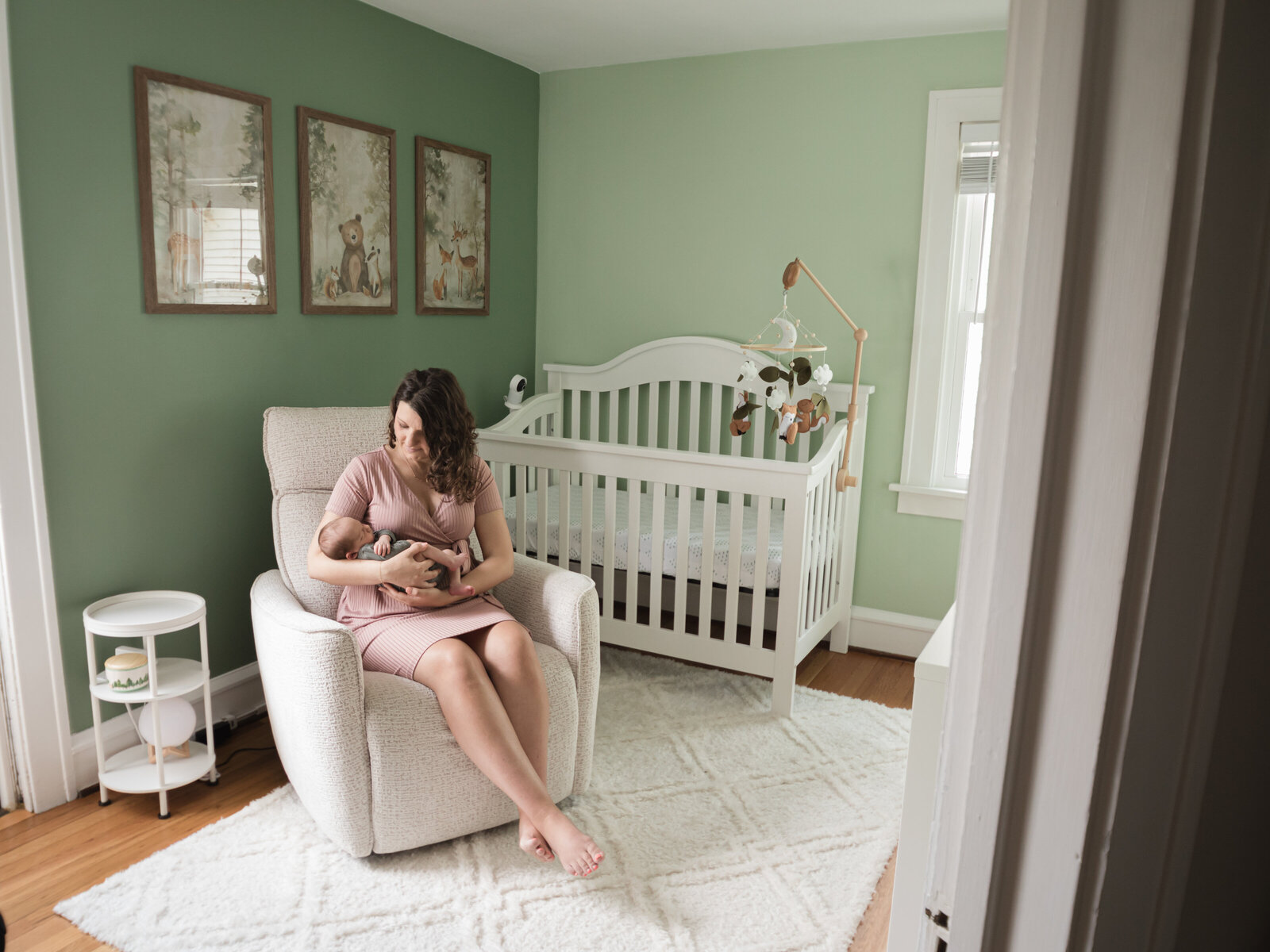 mom sitting in chair in nursery holding newborn baby boy 