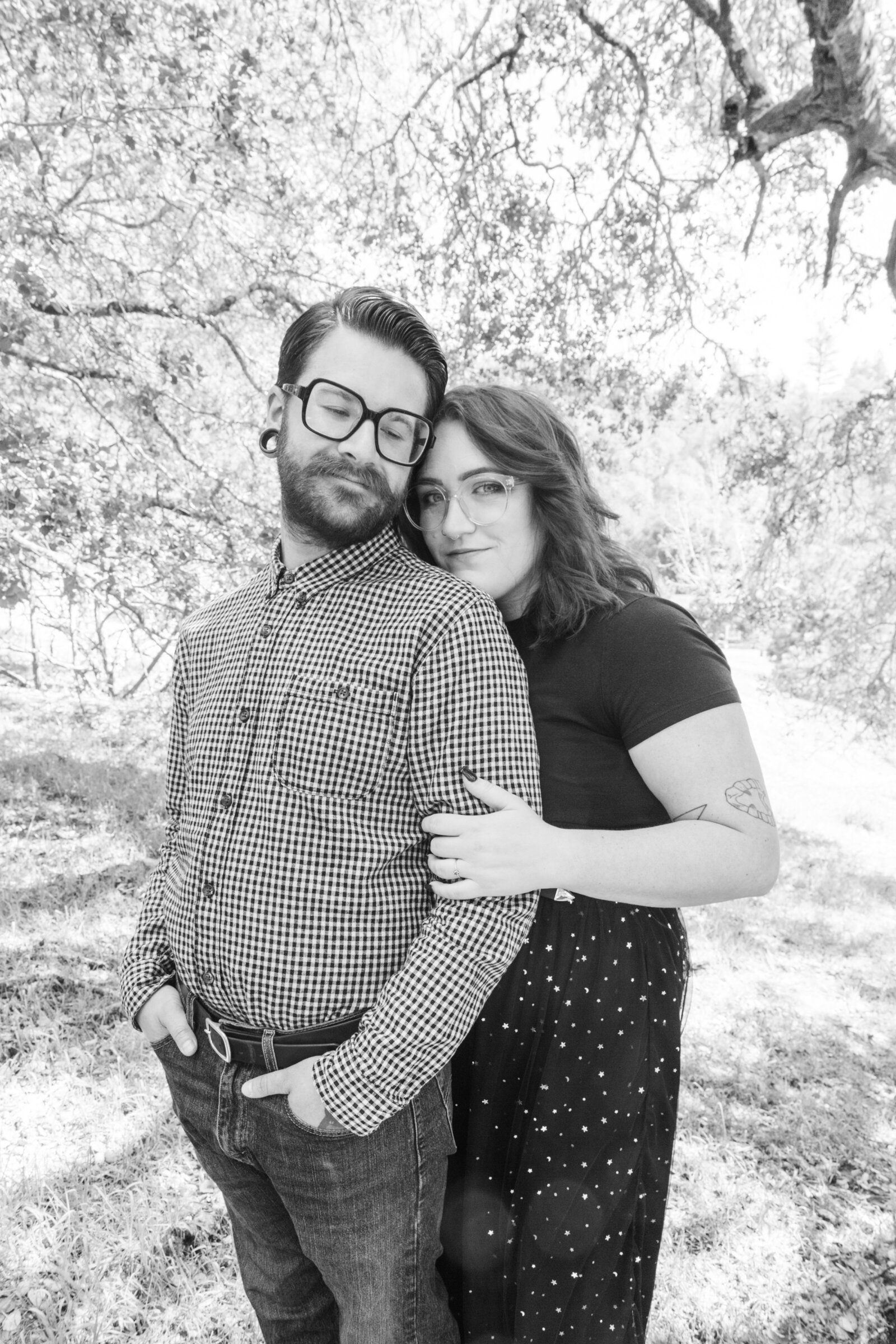An tattooed engaged couple poses for photos in a redwood forest in Santa Cruz, Ca.