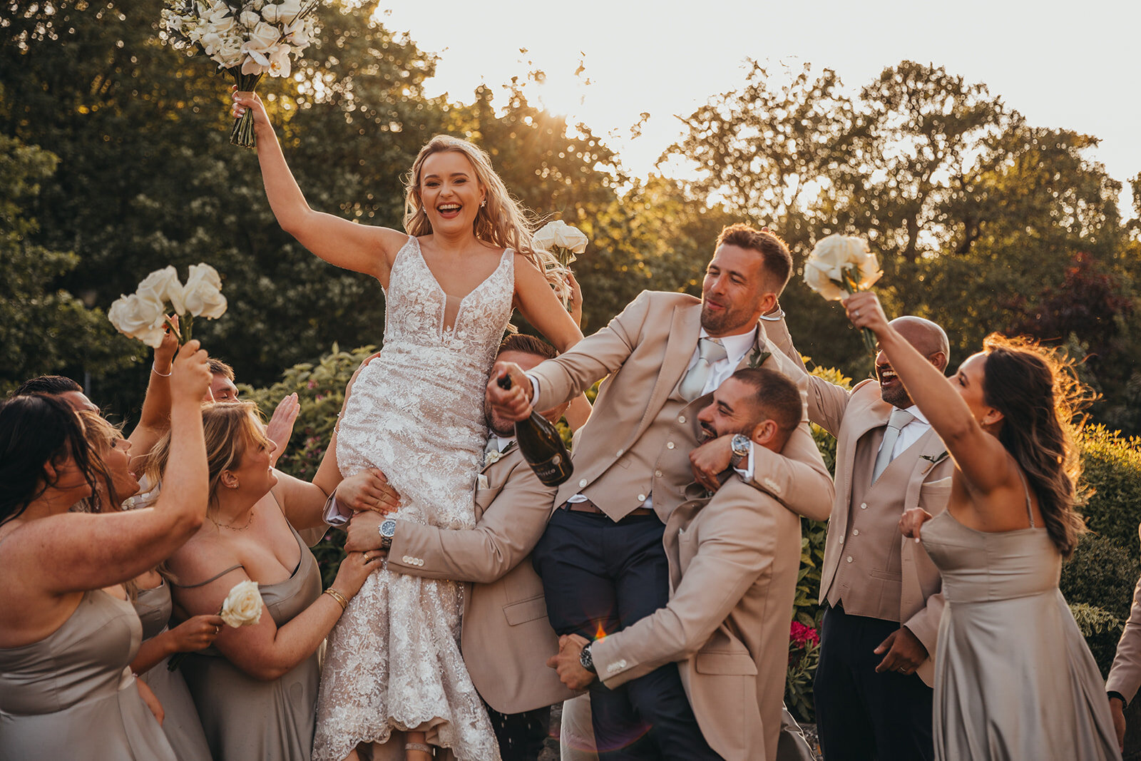 bride and groom are lifted up by their wedding party