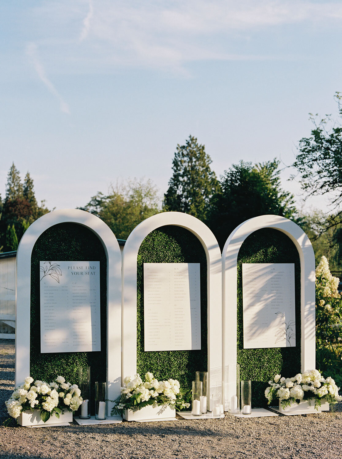 Seating chart display with modern arches and greenery