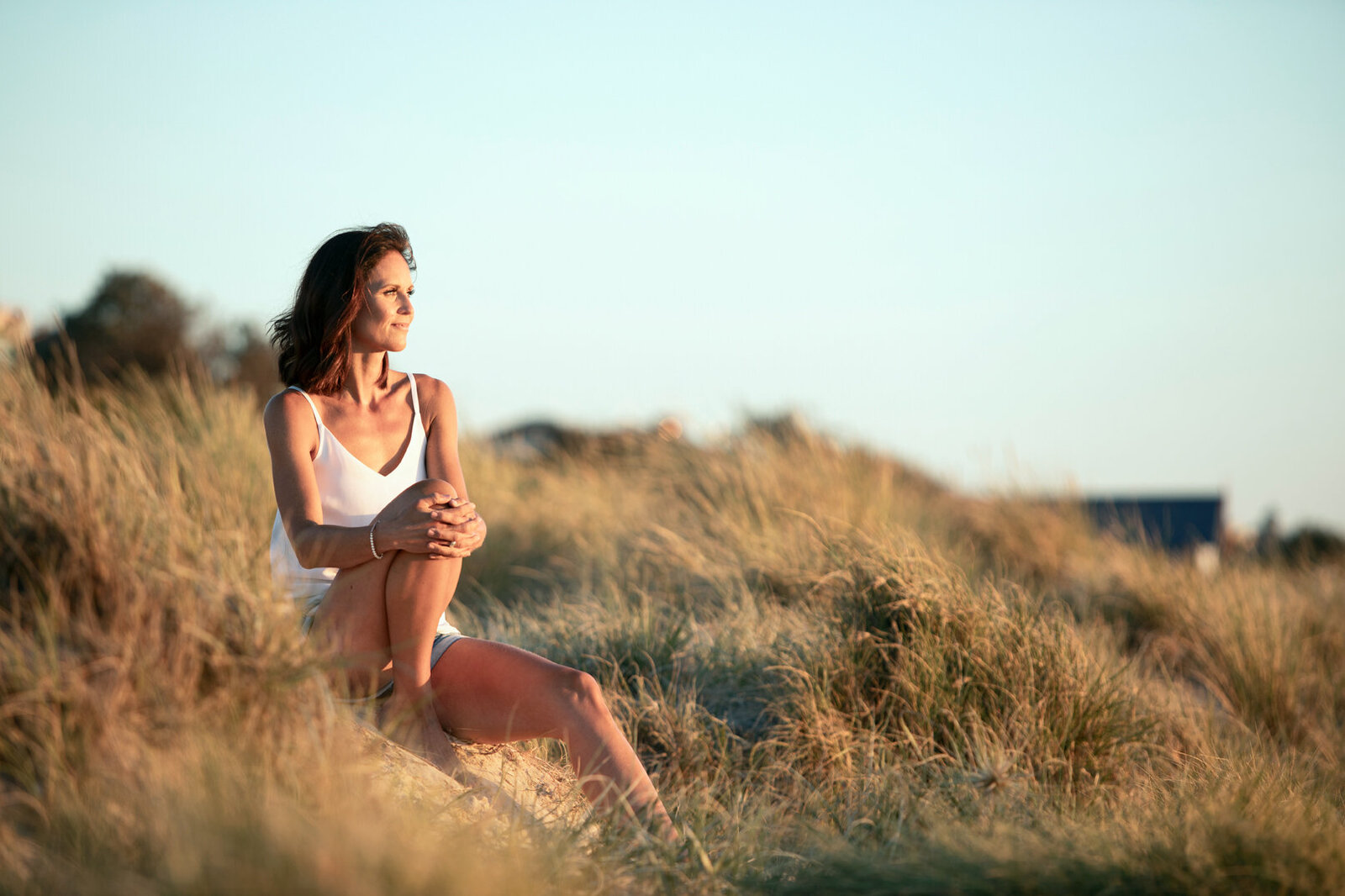 Lady sitting in long glass at the beach at sunset