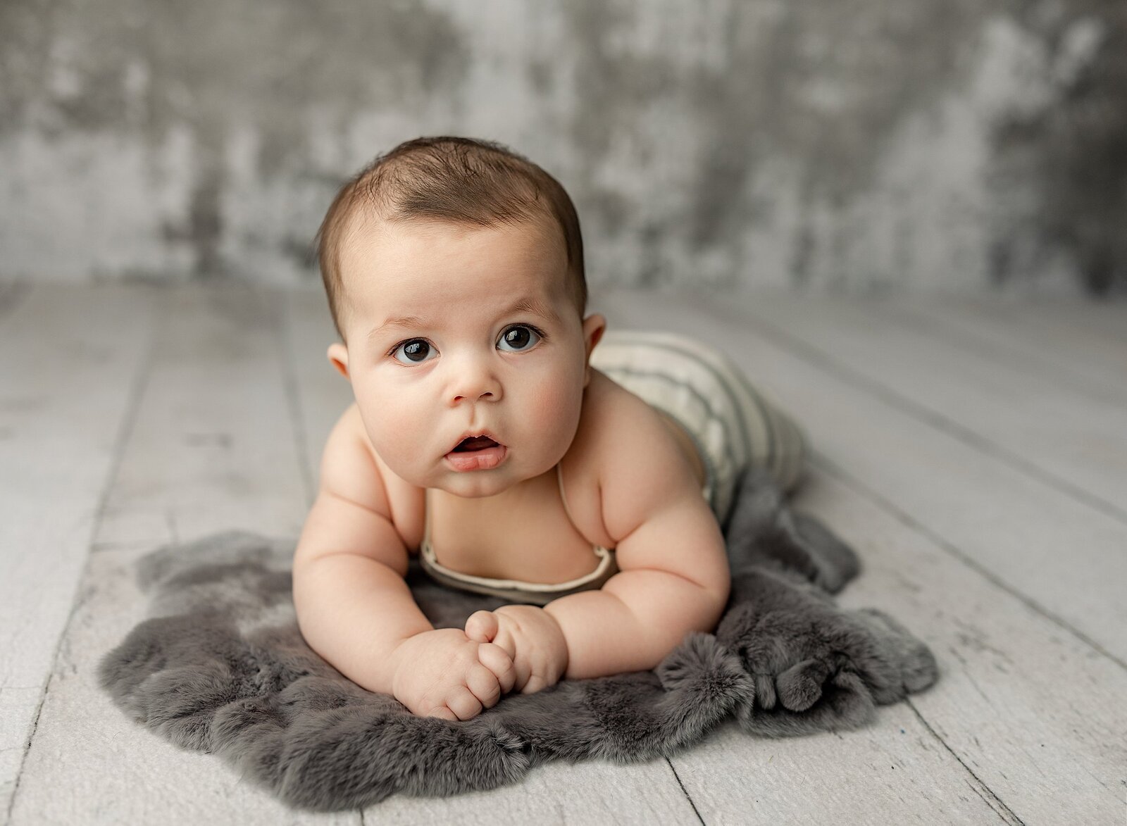 4 month old baby boy doing tummy time for his 4 month photo session in the quad cities.
