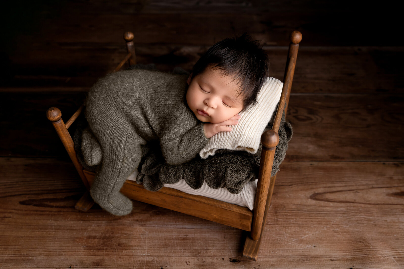 newborn photography sacramento, california. baby posed on wooden bed in a knitted outfit