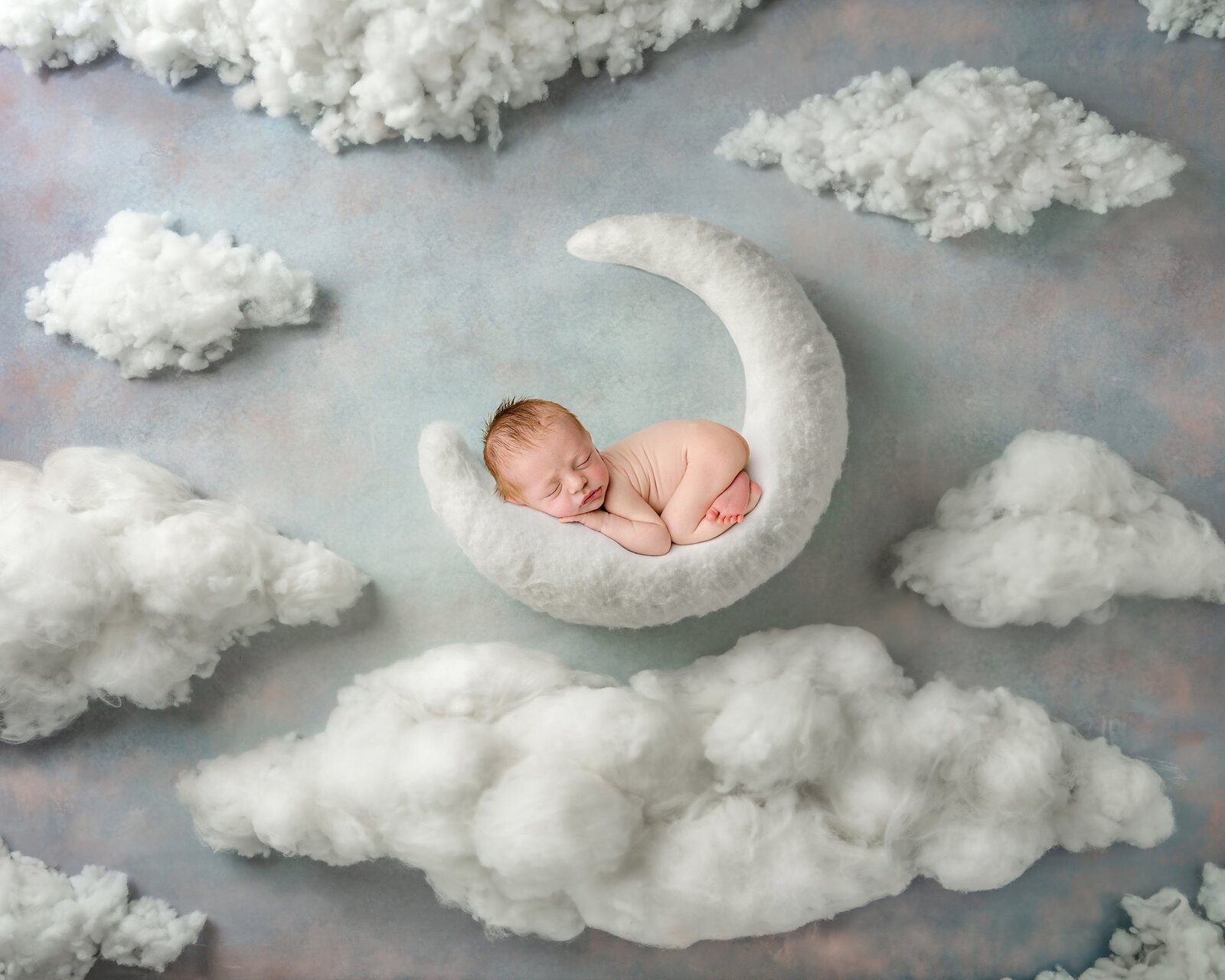 Baby boy posed on a moon with clouds in the quad cities
