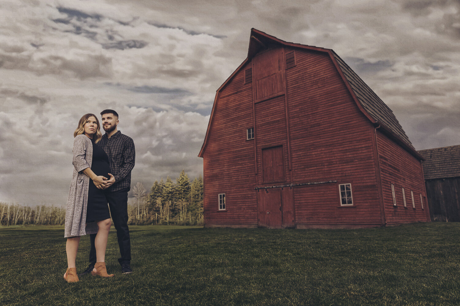 pregnant couple in front of a barn