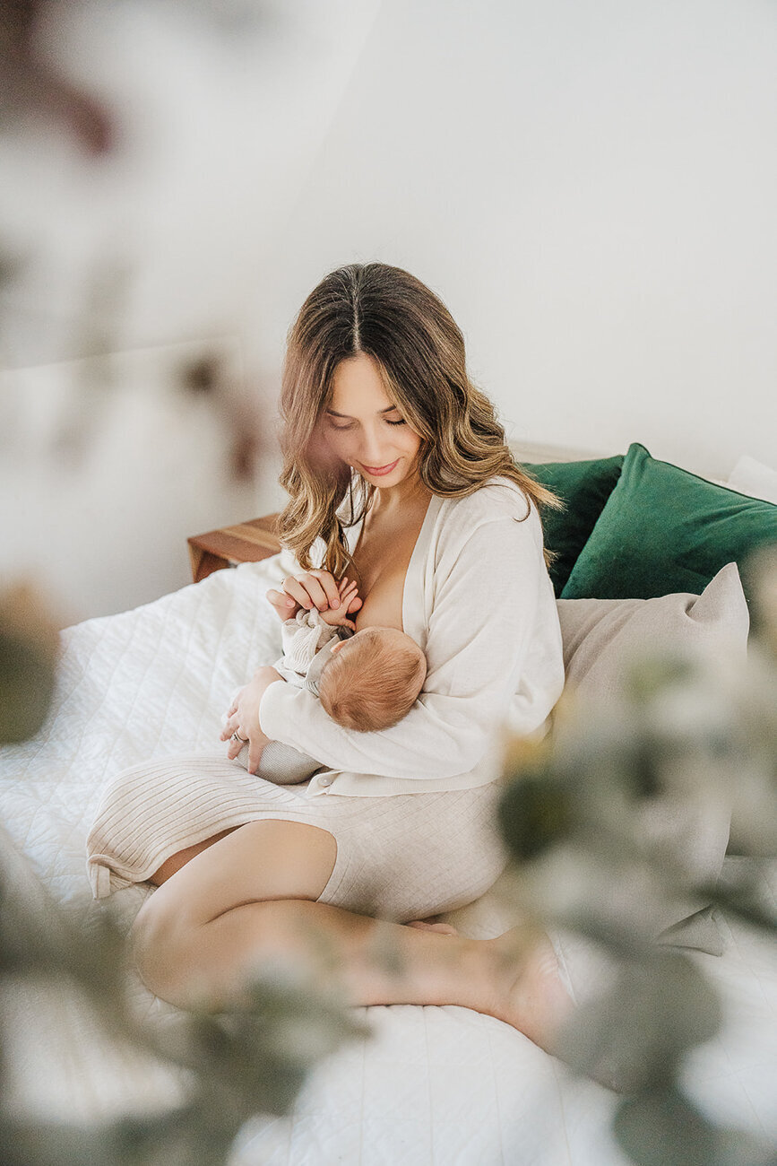 mom nurses baby on master bed