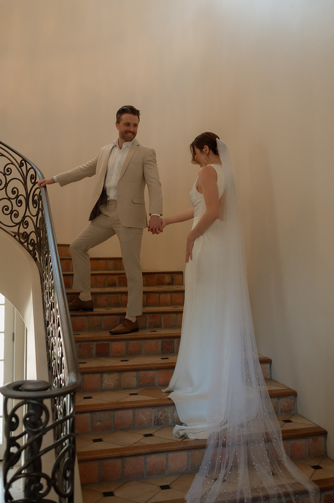 bride and groom holding hands walking up stairs