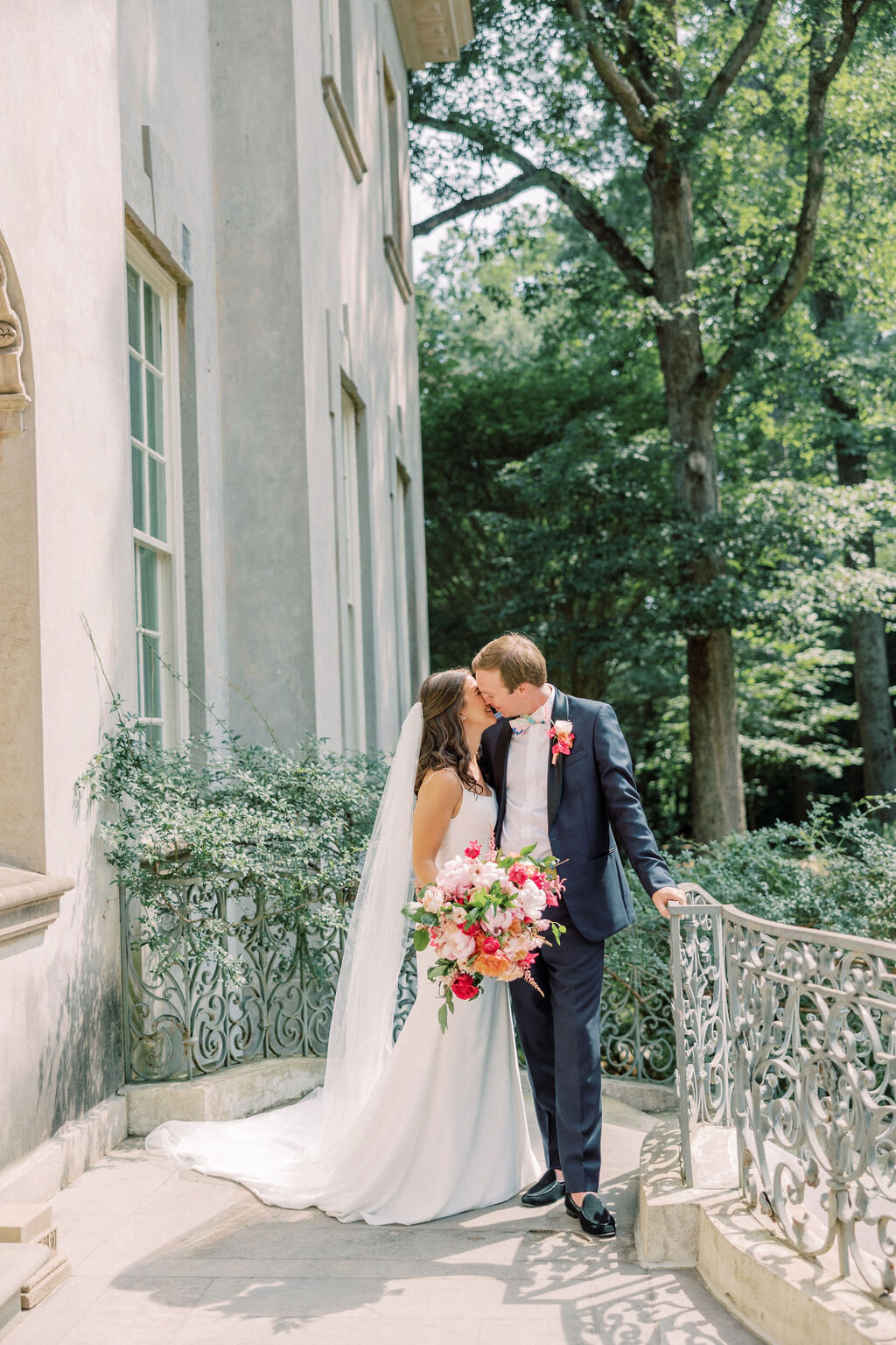 Bride kisses groom on the back steps of the Swan House