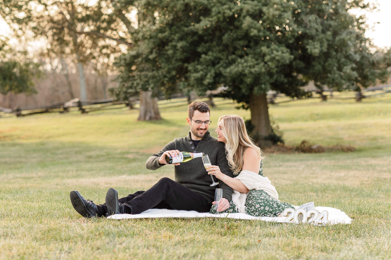 A couple celebrating their pregnancy at a park at sunset.