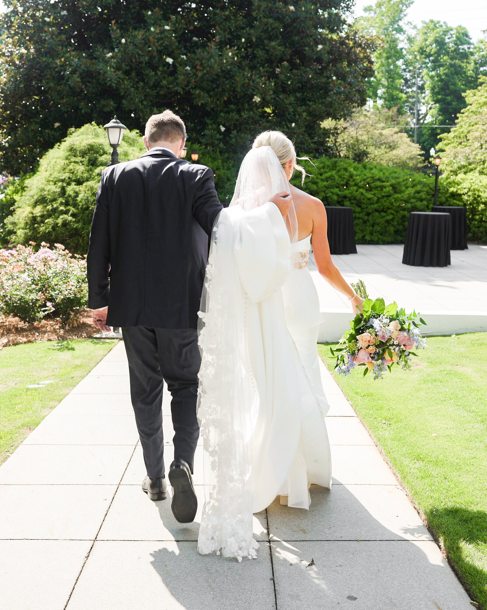 groom wearing black suit holding brides while silk dress and lace veil at Carlyle House in Atlanta Georgia