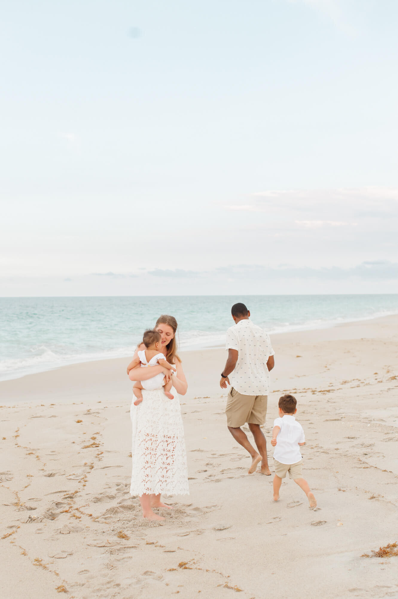 Family running playfully on the beach during their family beach session