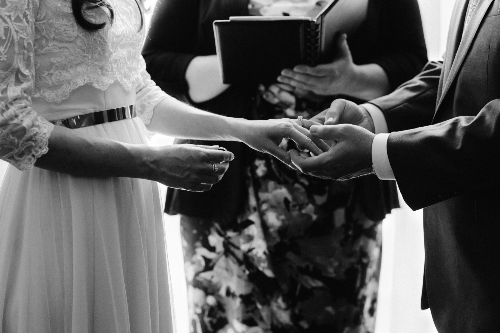 Black and white close up shot of the moment when the groom slides the ring on his bride's finger