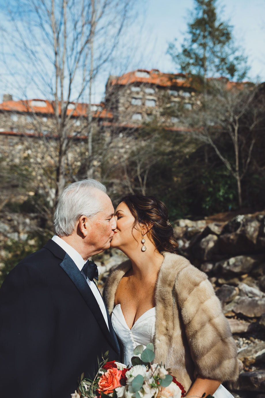 Bride and Groom kiss bathed in sunlight with the Grove Park in in Asheville NC in the background