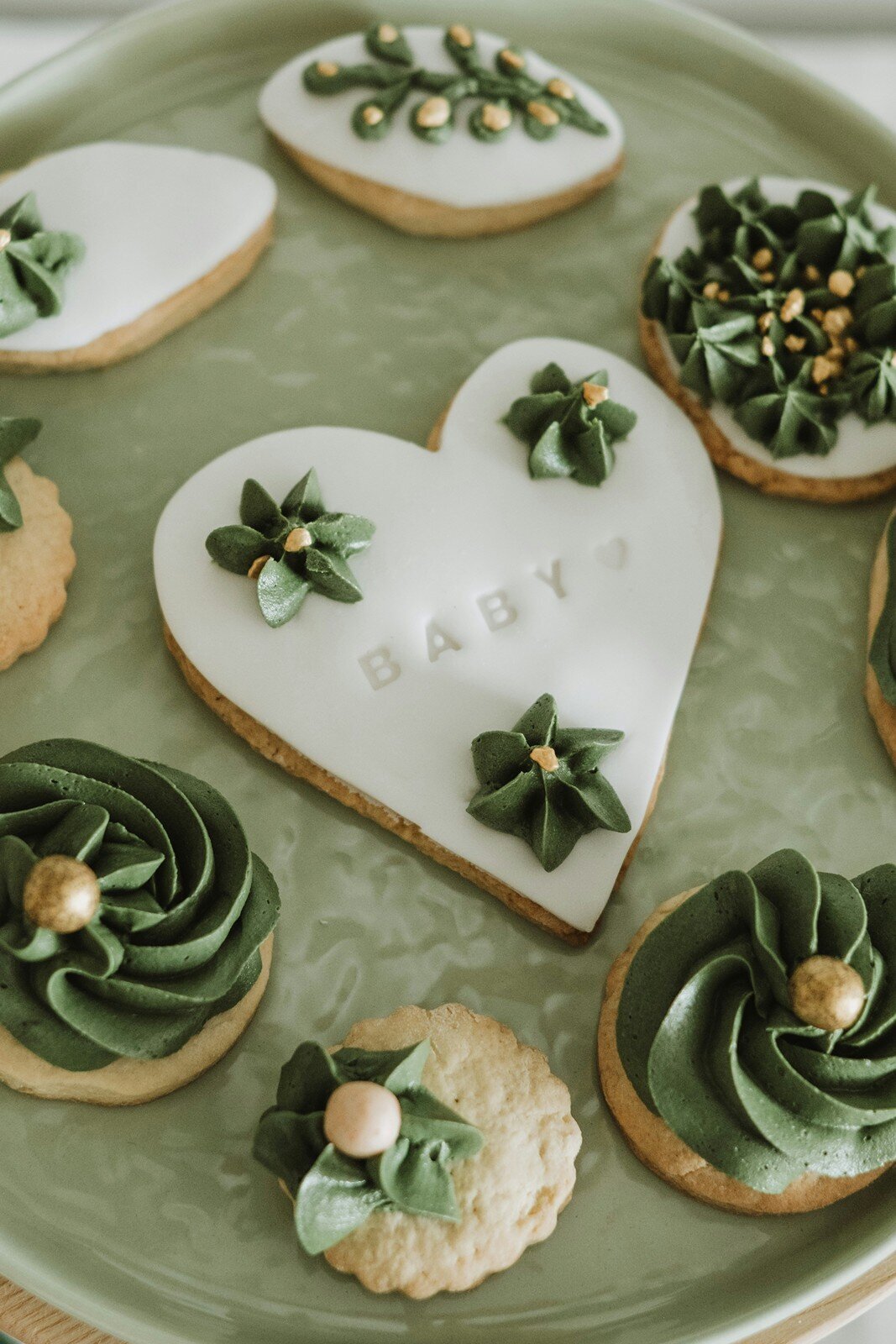 Heart-shaped baby shower cookie with green icing and “BABY” text