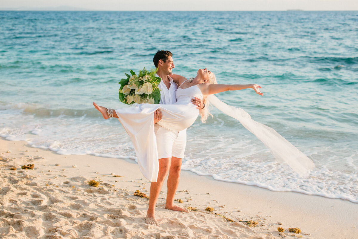 bride in groom's arms on the beach