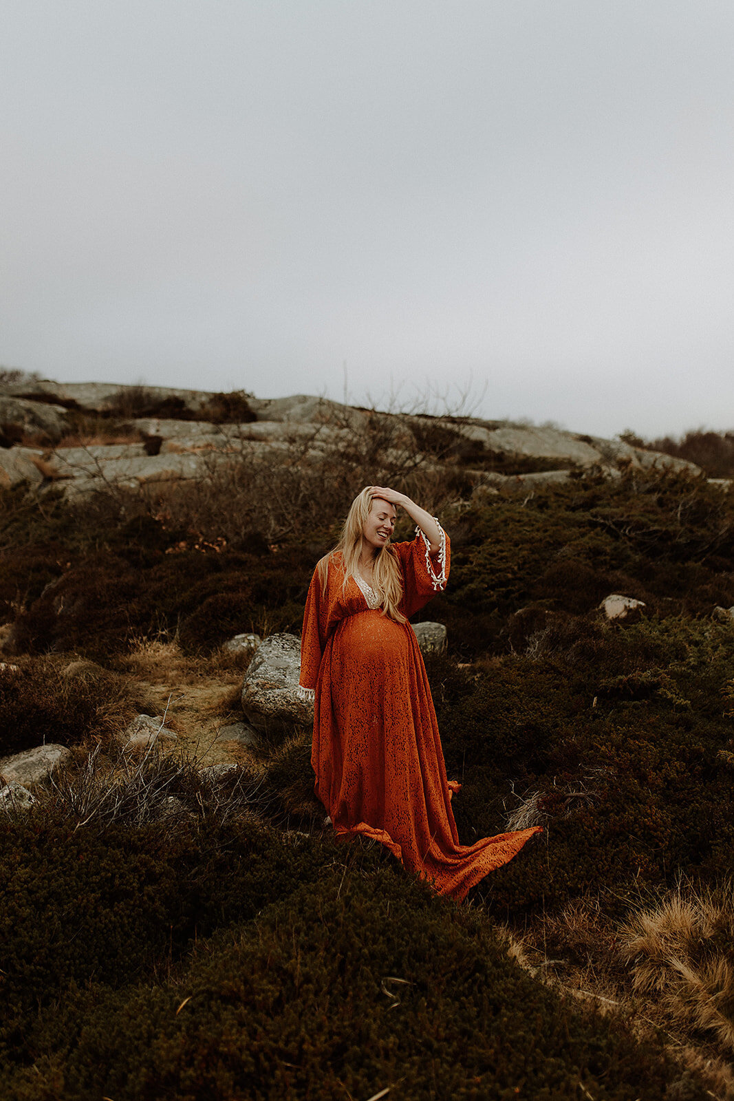 en gravid kvinna står i en orange gravidklänning