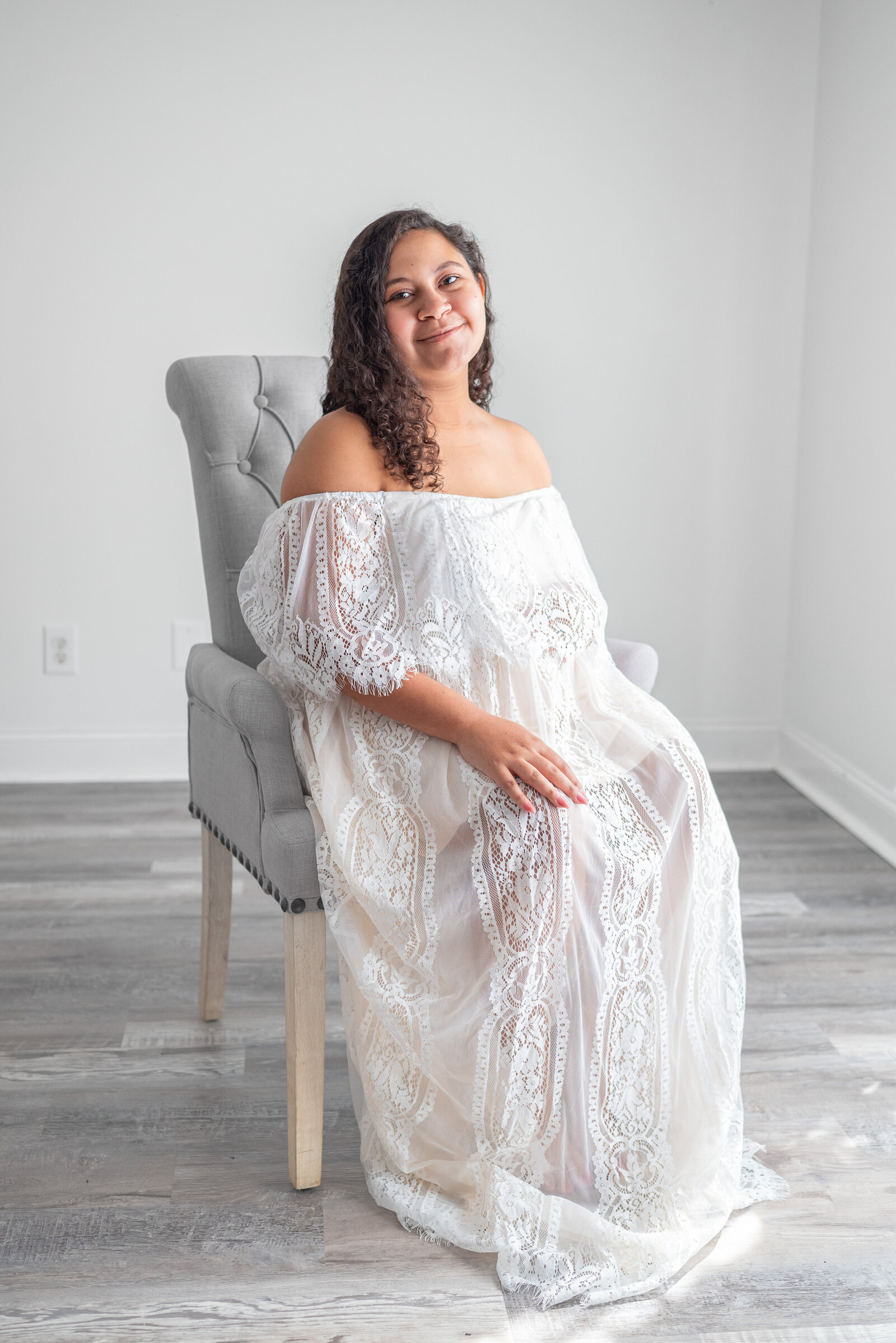 Pregnant woman sitting in a chair and posing for her maternity photos in  a Huntsville Alabama studio
