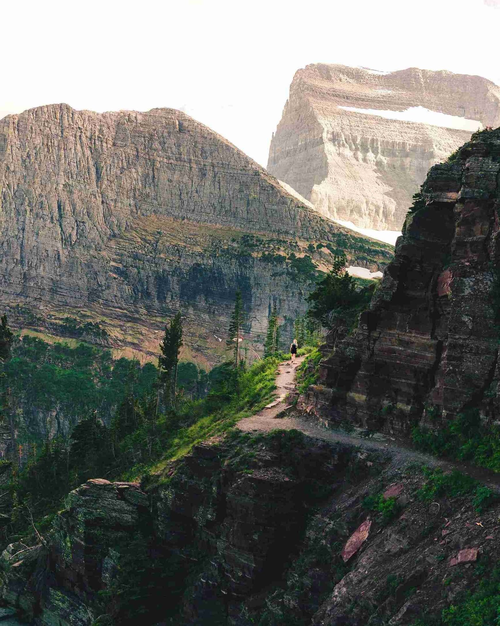 A scenic mountain landscape with a winding road leading through the lush greenery below.