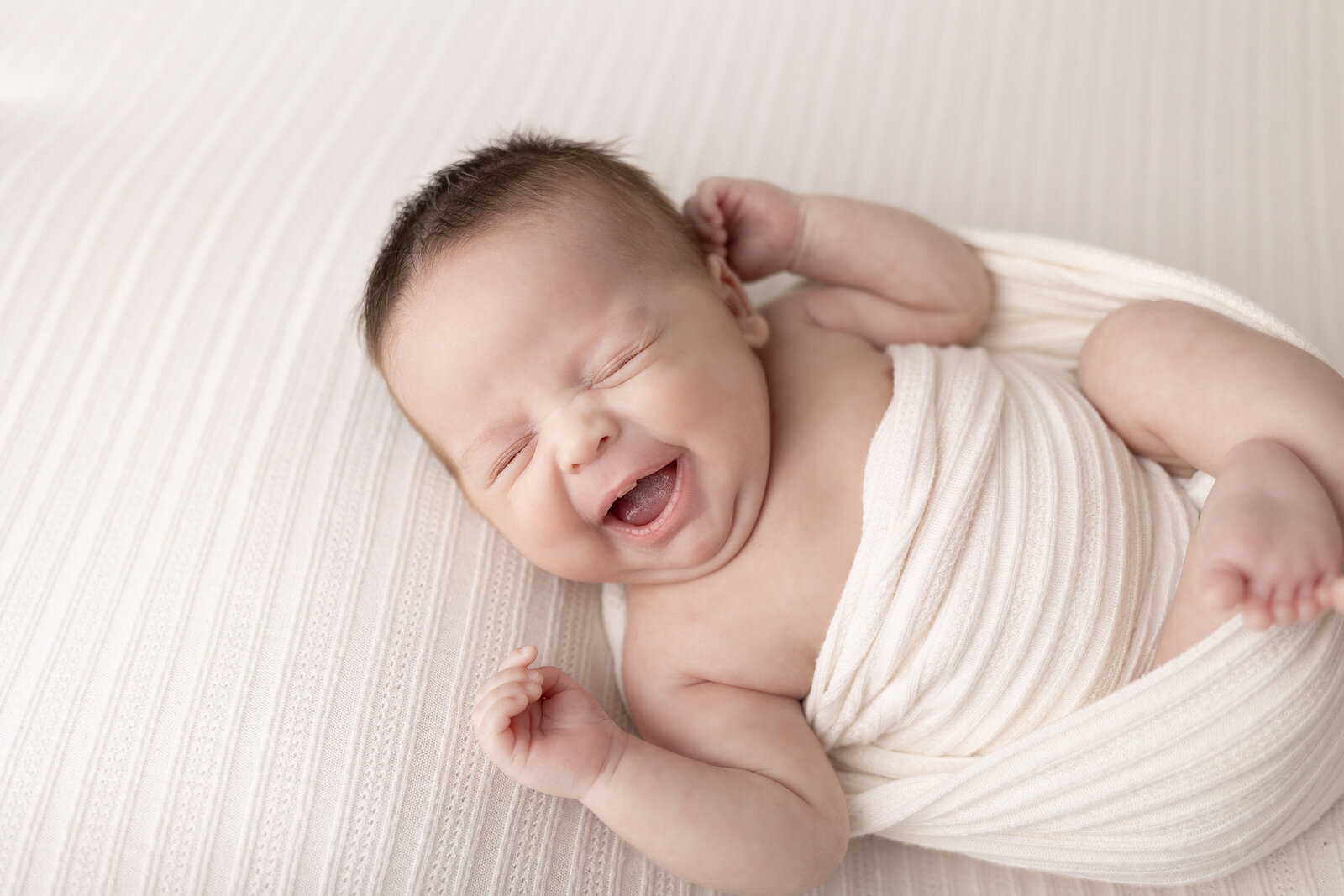 smiling newborn baby boy in white wrap