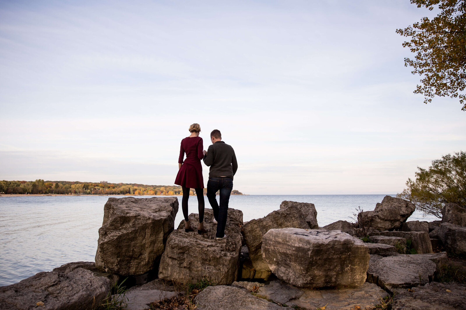 Couple on rocks at Toronto beach during engagement session.