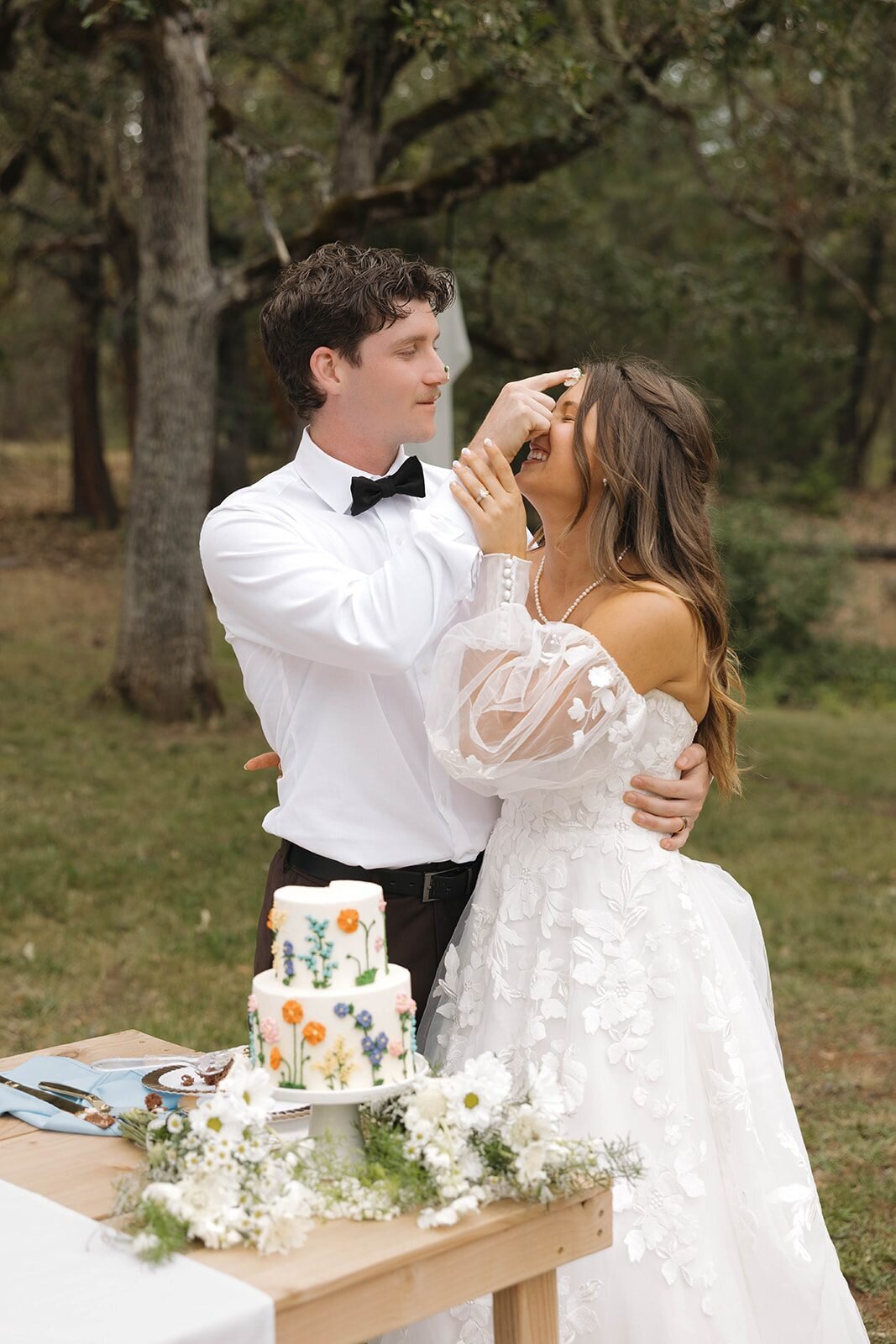 Groom feeding the bride cake at the outdoor reception