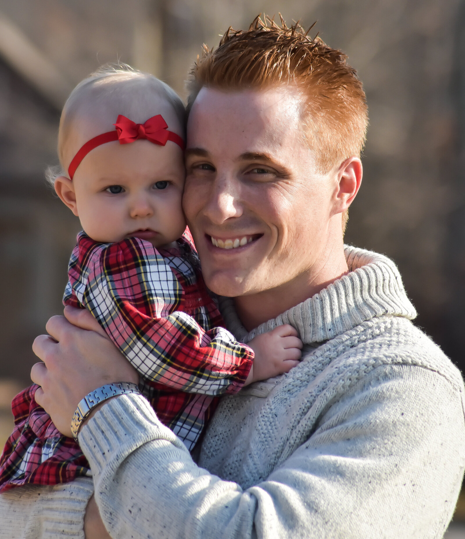 a father holding his infant daughter smiling at the camera photographed by Millz Photography in Greenville, SC