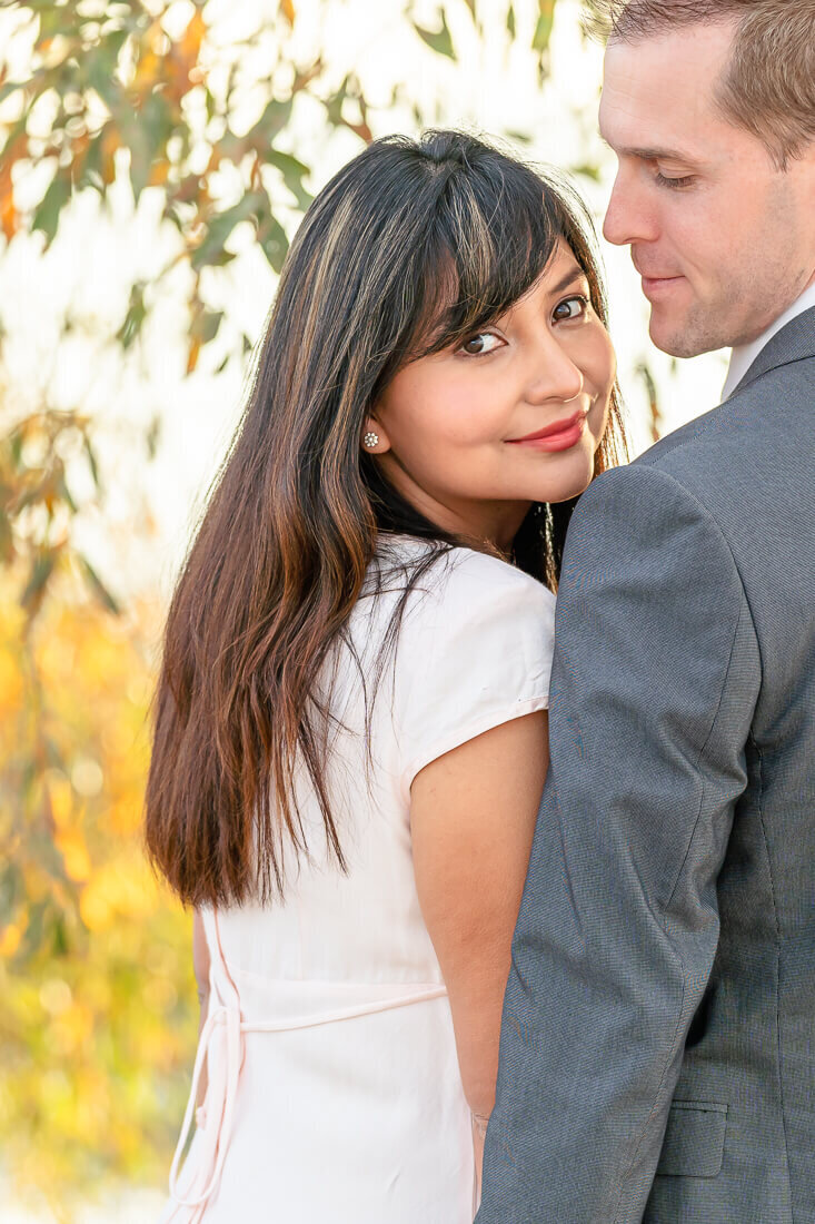 Utah engagement photography of a woman looking over her fiance's shoulder at Utah Lake  in the Fall